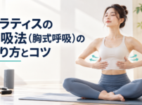 明るいスタジオのマットの上で肋骨に手を当てて呼吸する女性の実写写真
