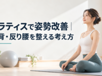 明るいスタジオのマットの上で背筋をすっと伸ばして座る女性の実写写真